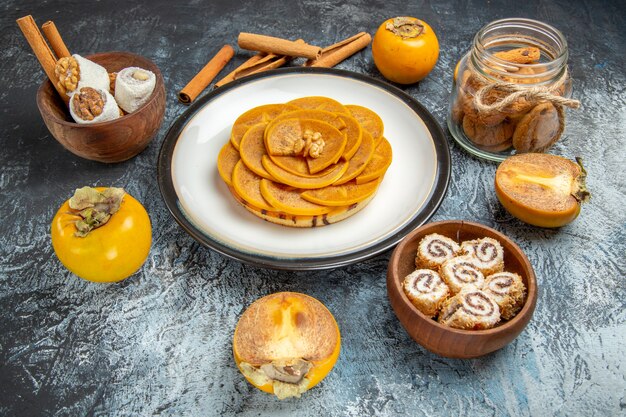 Vorderansicht der geschnittenen Persimone auf Pfannkuchen auf heller Oberfläche