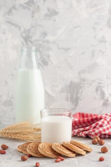 Vorderansicht der glasbecherflasche gefüllt mit milch und keksen erdnüsse spikes rot gestreiftes handtuch auf gefärbtem weißem hintergrund