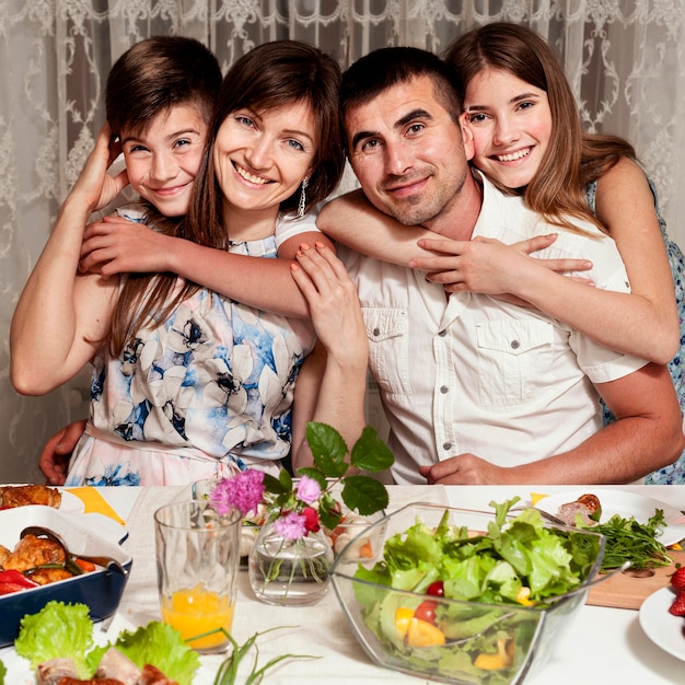 Kostenloses Foto vorderansicht der glücklichen familie, die am esstisch aufwirft