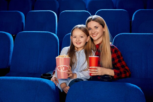 Vorderansicht der glücklichen Familie, die Zeit zusammen im leeren Kino verbringt