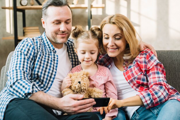 Vorderansicht der glücklichen Familie schauend im Handy