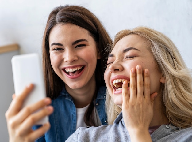 Vorderansicht der glücklichen Frauen, die lächeln und ein selfie nehmen