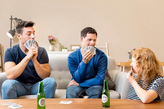 Vorderansicht der Gruppe von Freunden, die Karten zu Hause spielen und Bier haben