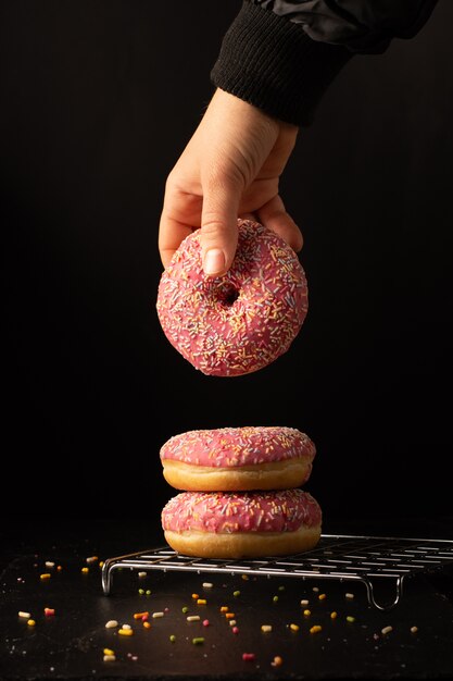 Vorderansicht der Hand glasierten Donut vom Stapel nehmend