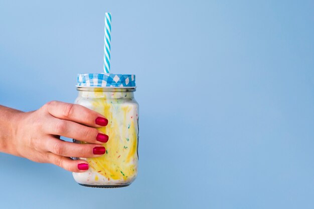 Vorderansicht der Hand und des Milchshakes auf blauem Hintergrund mit Kopienraum