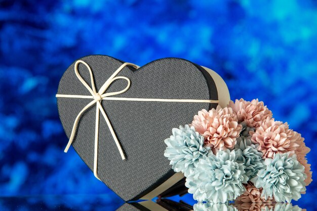 Vorderansicht der Herzgeschenkbox mit schwarzem Deckel und farbigen Blumen auf blauem abstraktem Hintergrund