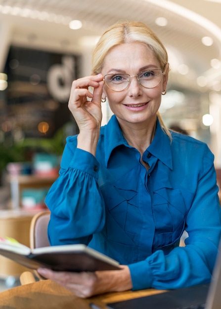 Vorderansicht der intelligenten älteren Geschäftsfrau mit Brille, die Agenda hält