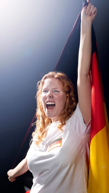 Kostenloses Foto vorderansicht der jubelnden frau, die deutsche flagge hält