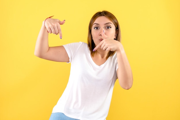 Vorderansicht der jungen Frau auf gelber Wand