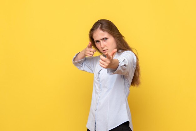 Vorderansicht der jungen Frau, die auf gelber Wand aufwirft