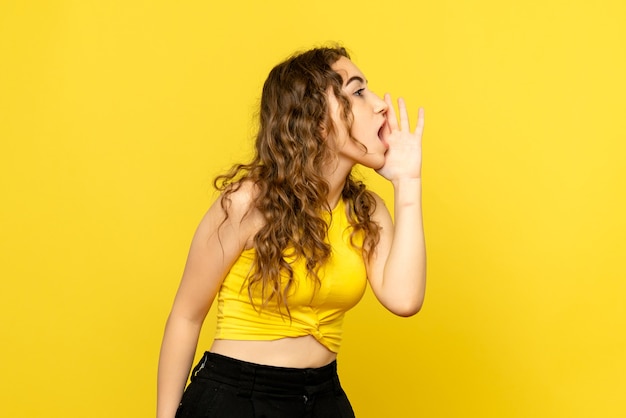 Kostenloses Foto vorderansicht der jungen frau, die gelbe wand anruft