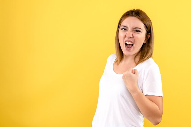 Vorderansicht der jungen Frau, die sich an gelber Wand freut