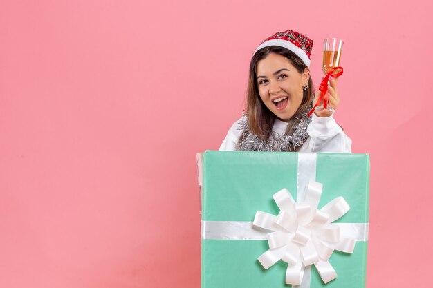 Vorderansicht der jungen Frau, die Weihnachten mit Getränk auf der rosa Wand feiert