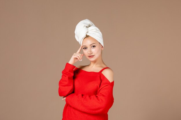 Vorderansicht der jungen Frau im roten Hemd mit Handtuch auf dem Kopf braune Wand