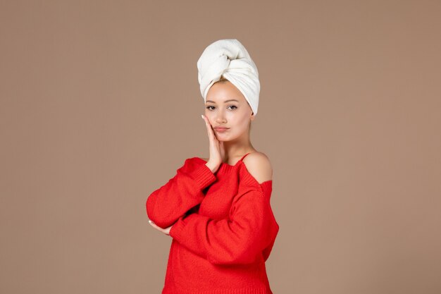 Vorderansicht der jungen Frau im roten Hemd mit Handtuch auf dem Kopf braune Wand