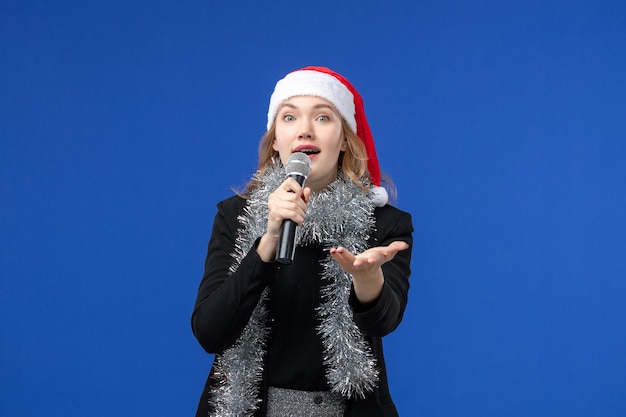 Vorderansicht der jungen Frau in der Karaoke-Party des neuen Jahres an der blauen Wand