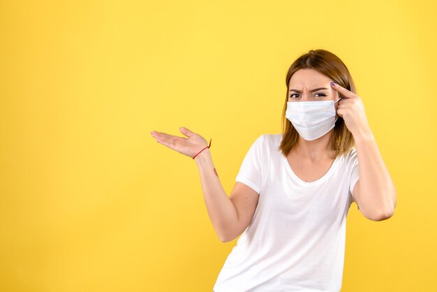 Vorderansicht der jungen Frau in der Maske auf der gelben Wand