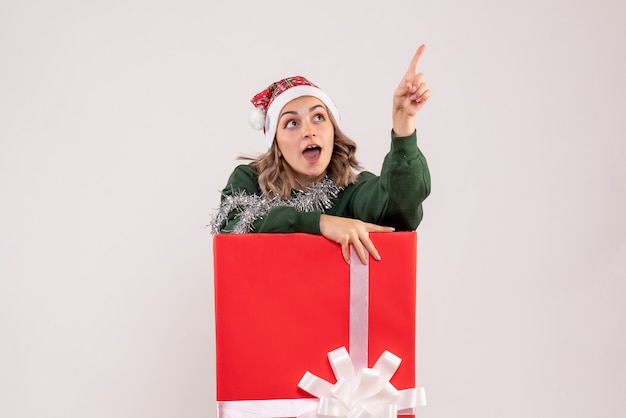 Kostenloses Foto vorderansicht der jungen frau in der roten geschenkbox an der weißen wand