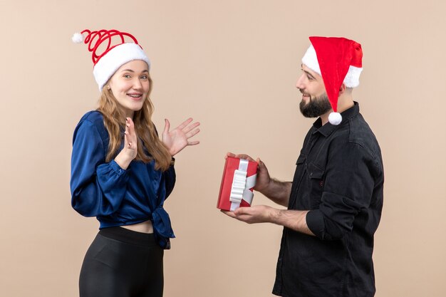 Vorderansicht der jungen Frau mit Mann, der ihr ein Geschenk an der rosa Wand gibt