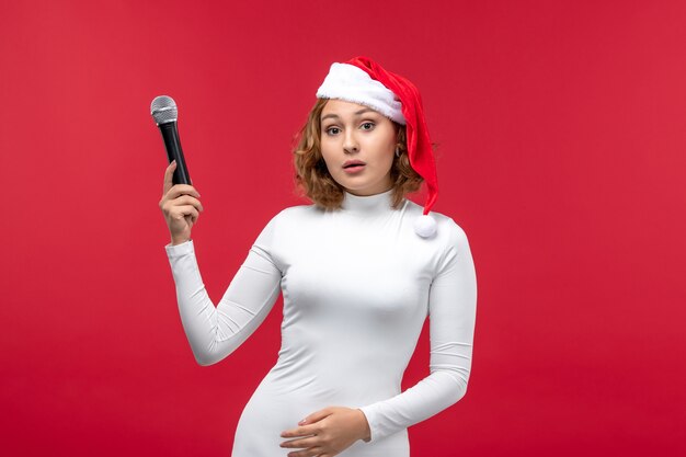 Vorderansicht der jungen Frau mit Mikrofon auf Rot