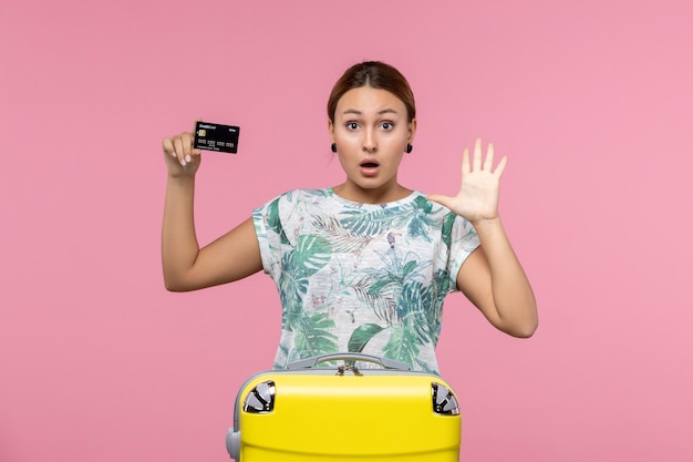Vorderansicht der jungen Frau mit schwarzer Bankkarte an der rosa Wand