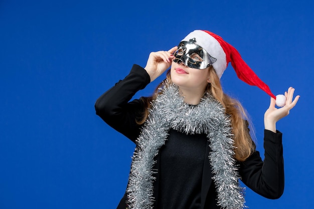 Vorderansicht der jungen Frau mit silberner Maske auf blauer Wand