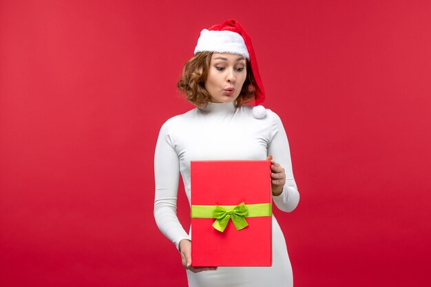 Vorderansicht der jungen Frau mit Weihnachtsgeschenk auf Rot