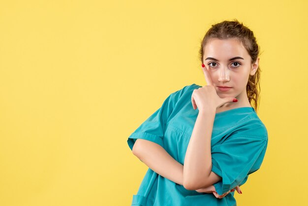 Vorderansicht der jungen Ärztin im medizinischen Hemd auf gelber Wand