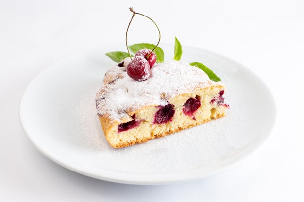 Vorderansicht der Kirschkuchenscheibe köstlich und lecker innerhalb der weißen Platte auf der weißen Oberfläche