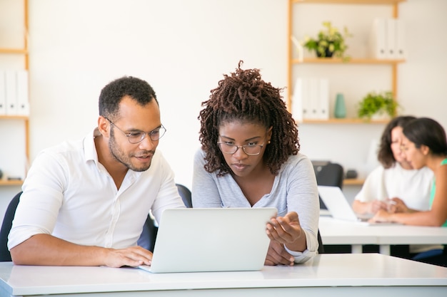 Vorderansicht der konzentrierten Angestellten, die mit Laptop arbeiten