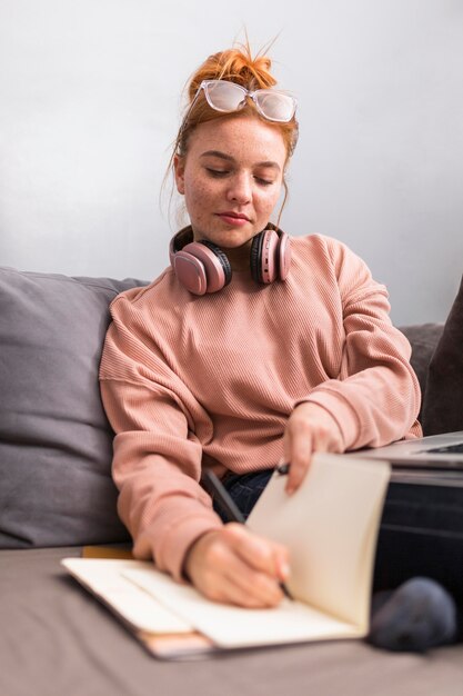 Vorderansicht der Lehrerin, die im Notizbuch während der Online-Klasse schreibt