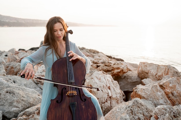 Kostenloses Foto vorderansicht der musikerin, die cello mit kopienraum spielt