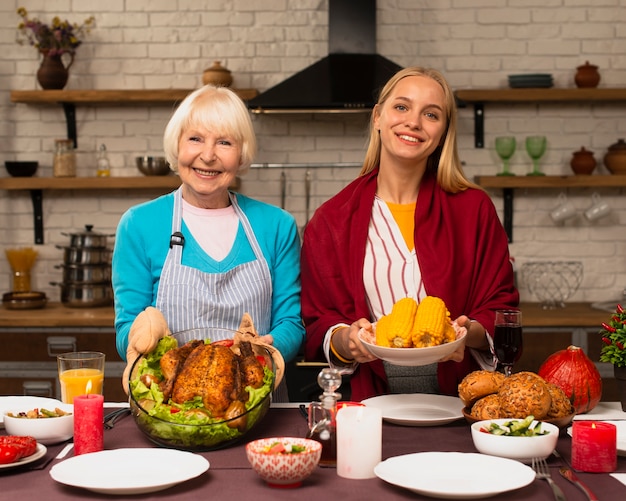 Kostenloses Foto vorderansicht der mutter und der tochter, die das lebensmittel halten