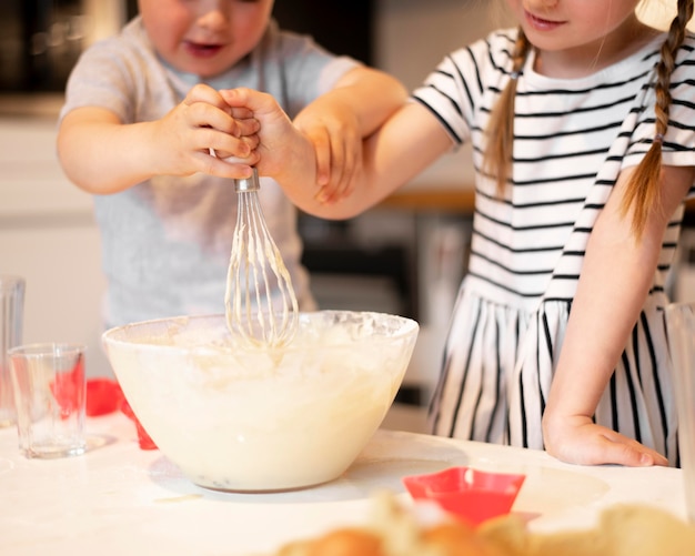 Vorderansicht der niedlichen Geschwister, die zu Hause kochen