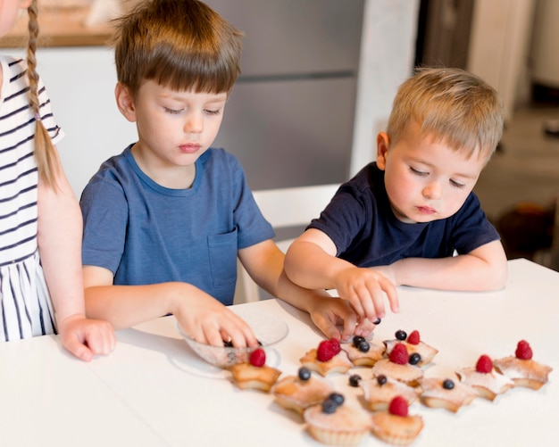 Kostenloses Foto vorderansicht der niedlichen geschwister, die zu hause kochen