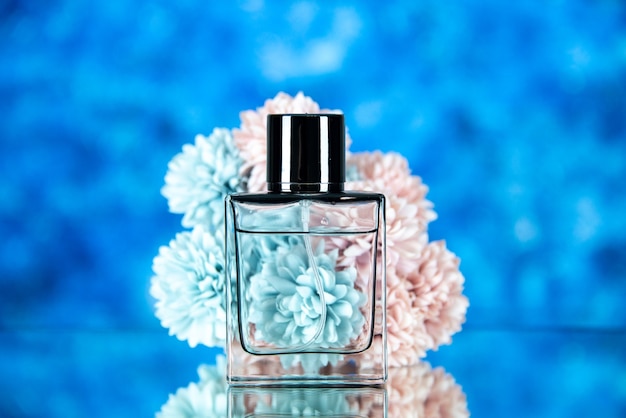 Vorderansicht der parfümflasche und der blumen auf blauem unscharfem hintergrund freier raum