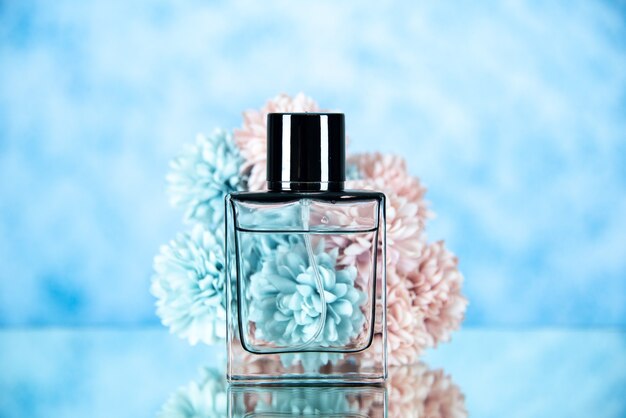 Vorderansicht der Parfümflasche und der Blumen auf hellblauem, unscharfem Hintergrund, freiem Raum