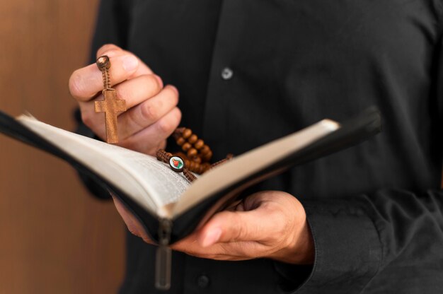 Vorderansicht der Person, die heiliges Buch und Rosenkranz hält