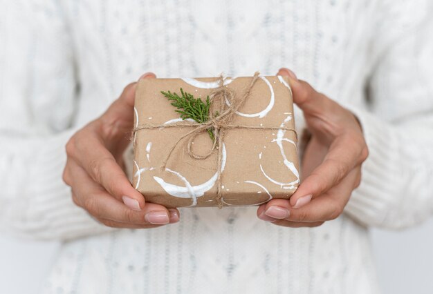 Vorderansicht der Person, die verziertes eingewickeltes Weihnachtsgeschenk hält