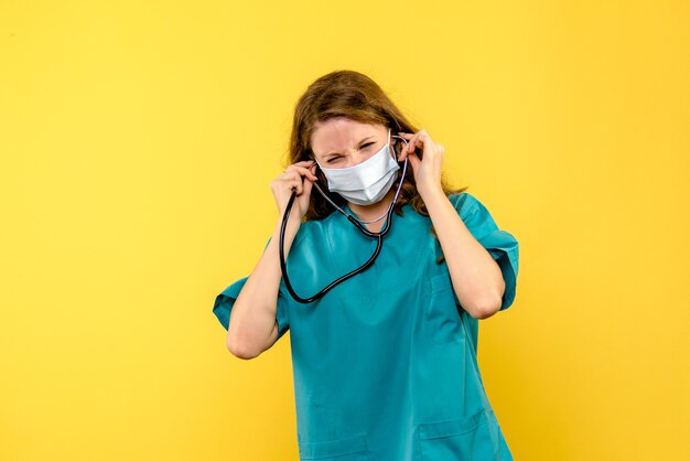 Vorderansicht der Ärztin in der Maske auf gelbem Boden Krankenhausmedizinergesundheit