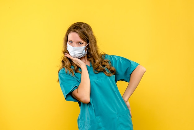 Vorderansicht der Ärztin in der Maske auf gelber Wand