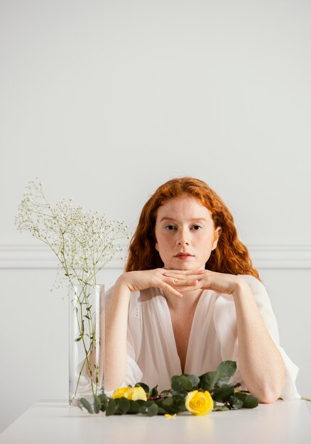 Vorderansicht der schönen Frau, die mit Frühlingsblumen und Vase aufwirft