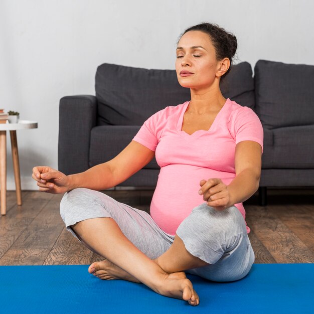 Vorderansicht der schwangeren Frau zu Hause, die Yoga tut