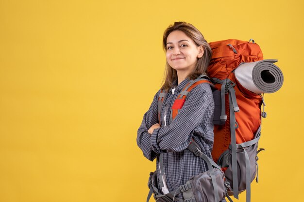 Vorderansicht der selbstbewussten Reisendenfrau mit rotem Rucksack, der Hände kreuzt