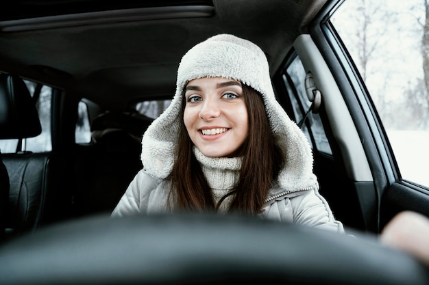 Kostenloses Foto vorderansicht der smiley-frau, die das auto für auf einer straßenfahrt fährt