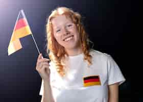 Kostenloses Foto vorderansicht der smiley-frau, die deutsche flagge hält