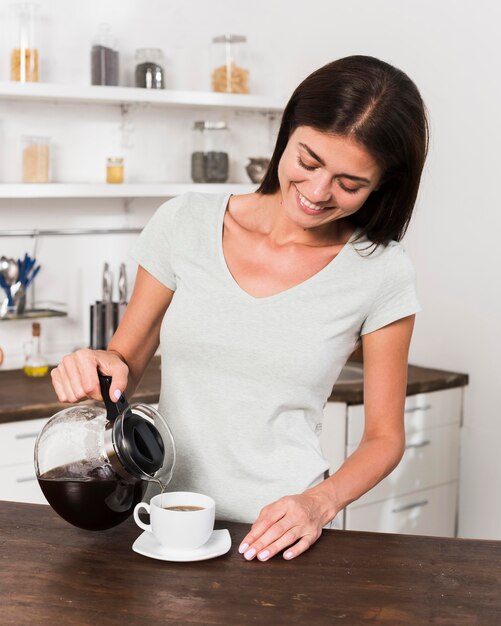 Vorderansicht der Smiley-Frau, die Kaffee zu Hause trinkt