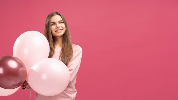 Vorderansicht der Smiley-Frau, die mit Luftballons aufwirft