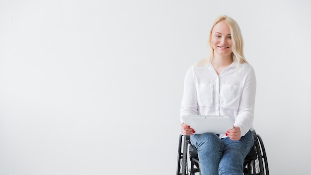 Vorderansicht der Smiley-Frau im Rollstuhl, der Tablette hält