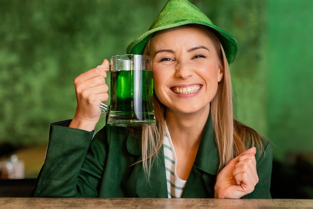 Vorderansicht der Smiley-Frau mit Hut, der st feiert. Patricks Tag mit Getränk